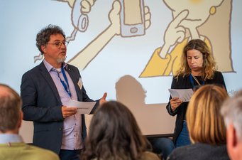 SW-Jahrestagung22_Saal_Moderation3_Foto_FlorianMaas_MESaar Nils Grützner und Stephanie Vogel moderieren im Saal. Akteure stellen Anliegen für den Open Space vor.